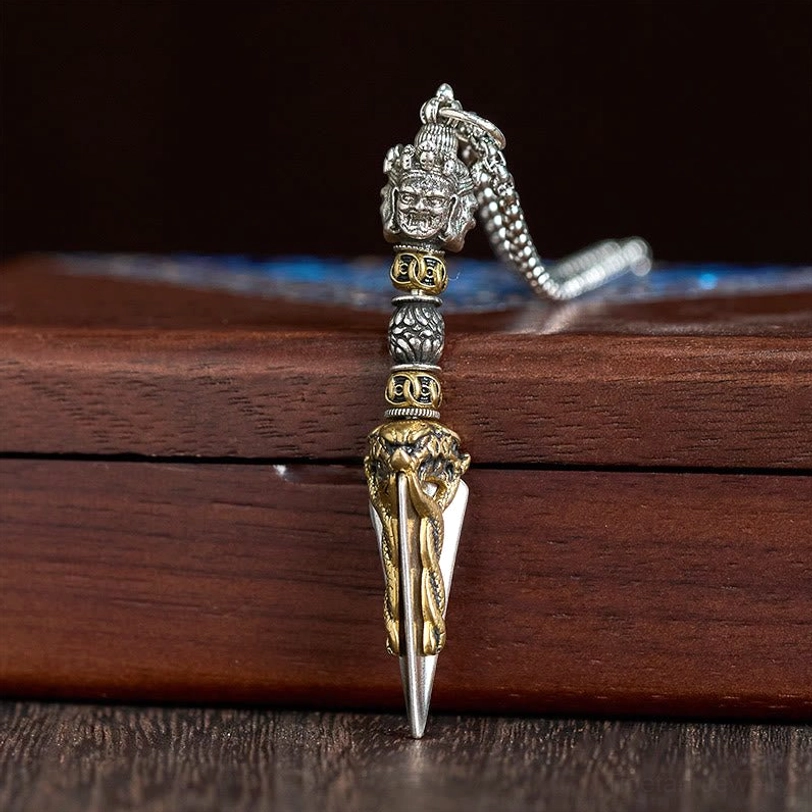 Tibetan Vajra Kila pendant displayed on wooden storage box with silver chain showing side profile and craftsmanship