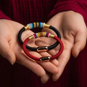 Handmade red and black Tibetan protection bracelets with magnetic clasps held in hands, showing woven knot detail
