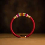 Red braided Tibetan Vajra Knot protection bracelet with magnetic metal clasp, handwoven cord, flat lay view