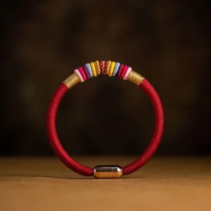 Red braided Tibetan Vajra Knot protection bracelet with magnetic metal clasp, handwoven cord, flat lay view