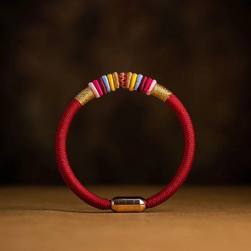 Red braided Tibetan Vajra Knot protection bracelet with magnetic metal clasp, handwoven cord, flat lay view