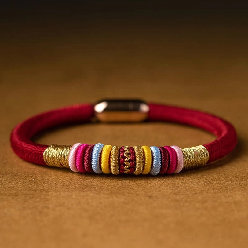 Red woven cord Tibetan protection bracelet with magnetic metal clasp and colorful decorative knots, top view
