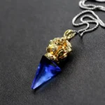 Blue Tibetan Vajra Liuli crystal pendant necklace with gold tone cap on dark background