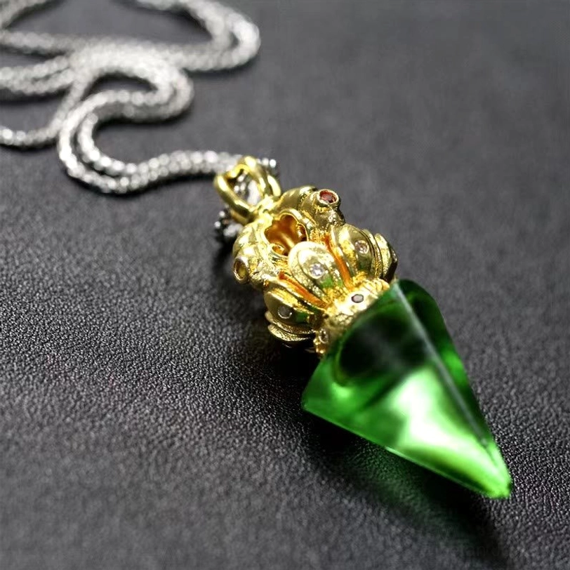 Close up of green Tibetan pendant necklace showing ornate metalwork and Liuli crystal texture