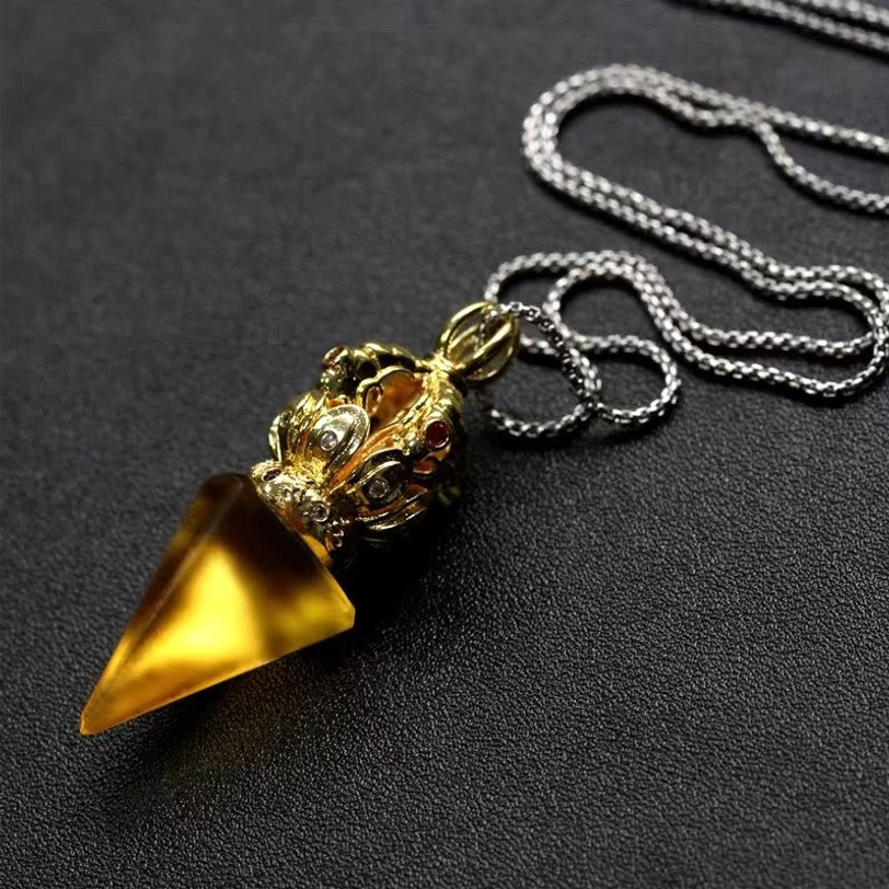 Yellow Tibetan Vajra Liuli crystal pendant necklace with gold tone cap on dark tabletop