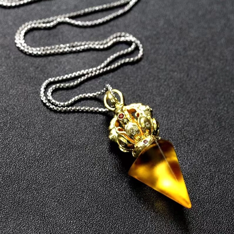 Close side view of yellow Tibetan pendant necklace with amber Liuli crystal and ornate top