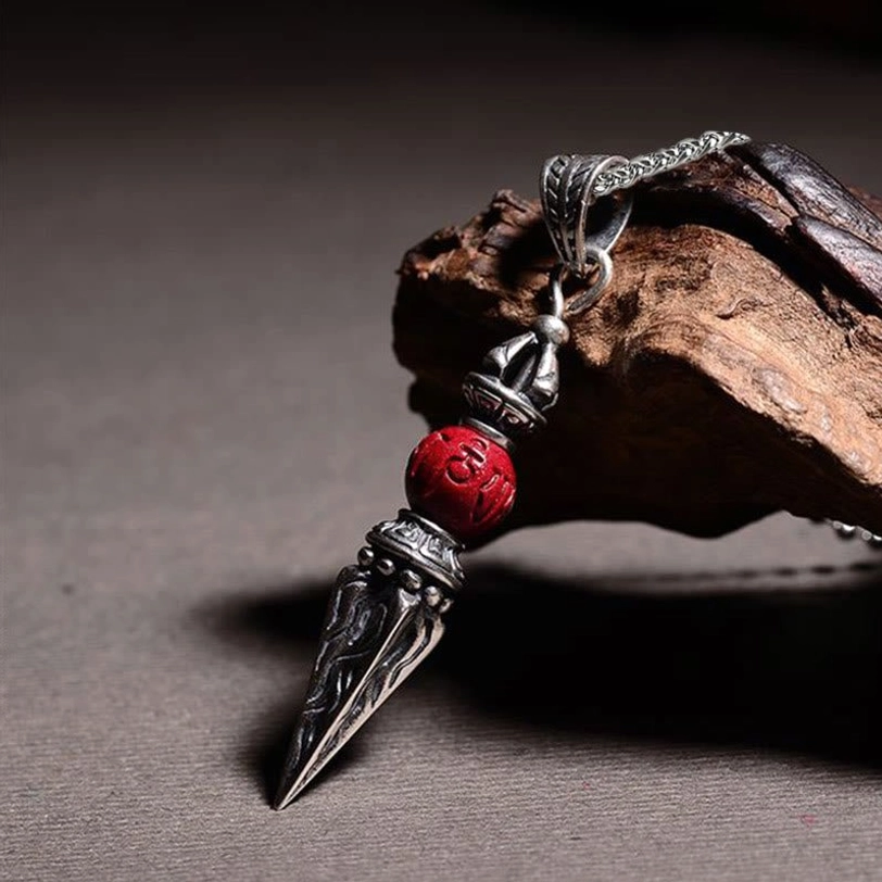 Three-quarter view of Tibetan vajra necklace displaying filigree silver work and Buddhist mantra cinnabar bead