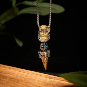 Sacred Tibetan Buddhist Vajra pendant hanging vertically showing intricate enamel bead detail, pointed spike, and gold-silver dual tone finish on wooden surface