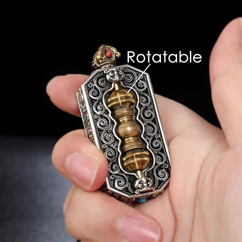 Hand-held side view of rotatable Tibetan dorje vajra pendant showcasing golden core and carved filigree frame with gemstone details