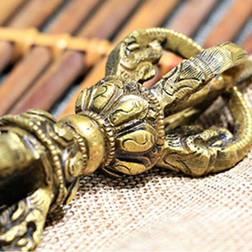 Side close-up of vajra dorje showing highly detailed 3D carved Buddhist religious designs in vintage bronze copper finish