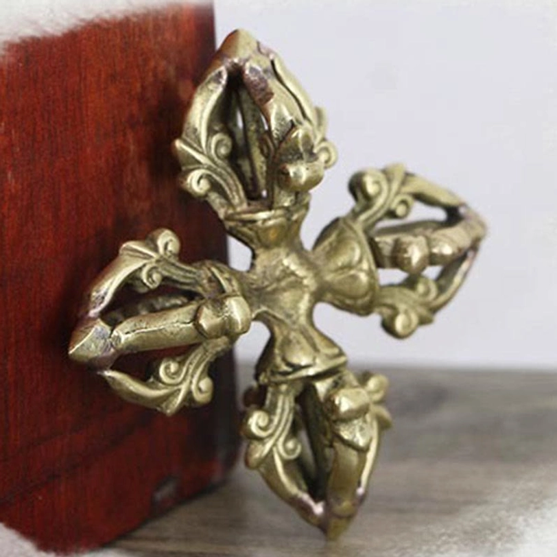 Tibetan vajra ritual symbol front view displaying symmetrical 5-prong cross structure with floral scroll carvings and aged bronze patina
