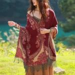 Tibetan vine leaf paisley shawl in burgundy and tan worn as travel wrap on model at lakeside