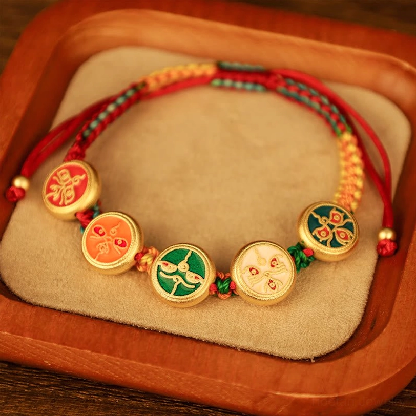 Tibetan red braided rope luck bracelet with five distinct enamel prosperity charms and gold-plated edges on wooden velvet pad