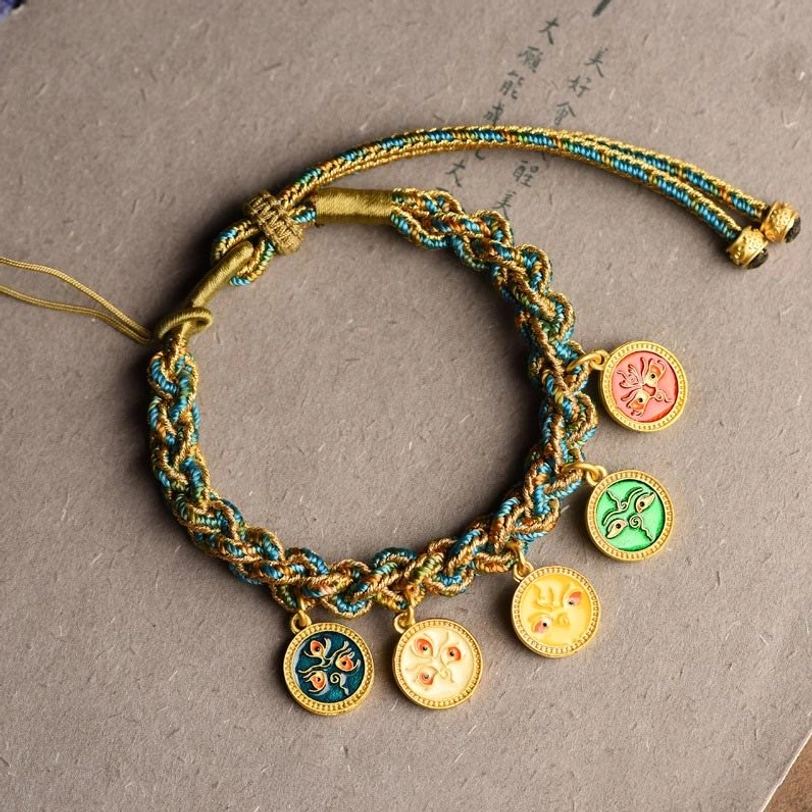 Multi-color enamel charm bracelet with adjustable pull cord, overhead view on grey background showing all five wealth deity pendants