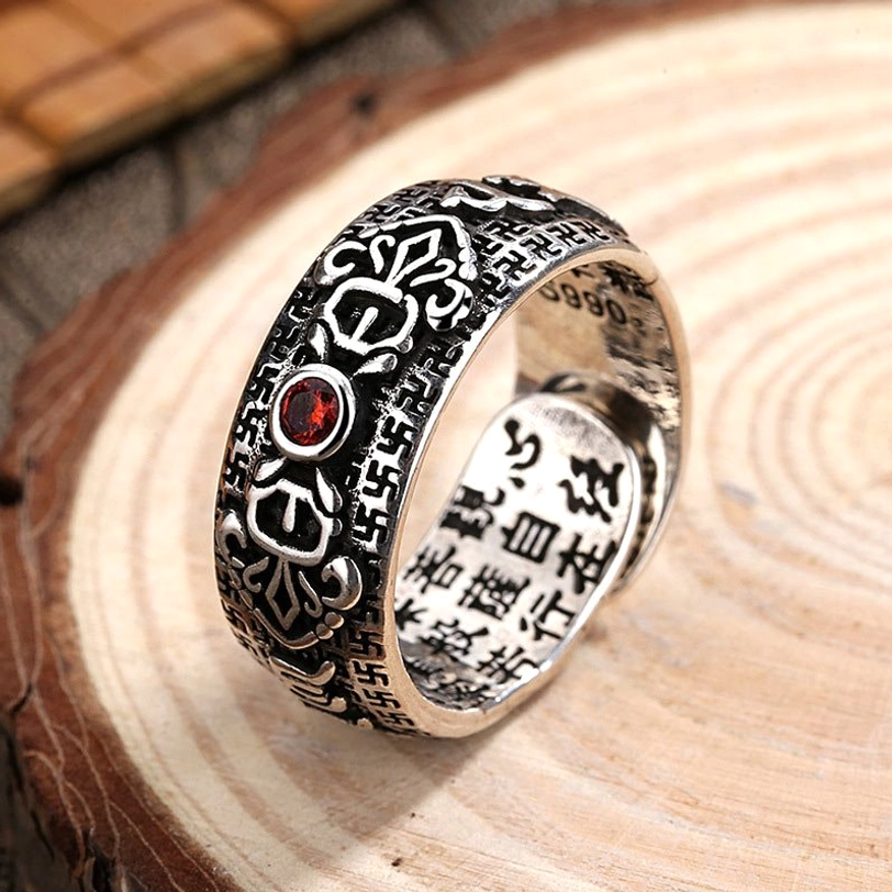 Tibetan copper ruby wealth ring adjustable band 3/4 side view showing engraved Buddhist scriptures and red gemstone on vintage silver finish