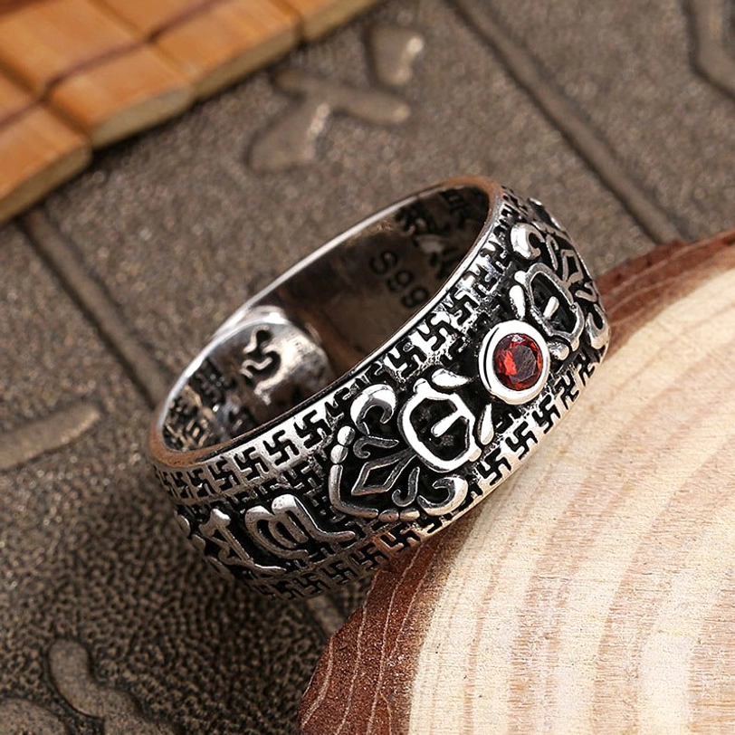 Low angle side view of Tibetan Buddhist copper ring with red side gem engraved patterns and retro silver-toned metal finish