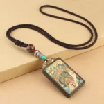 Tibetan Five Gods of Wealth Thangka ebony wood pendant necklace with braided cord and decorative beads, three-quarter view