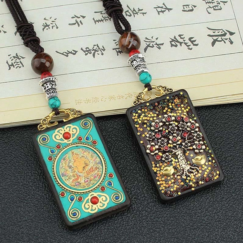 Two Tibetan Five Gods of Wealth thangka pendants showing turquoise enamel design and gold money tree decoration with brown beaded rope necklace on vintage paper