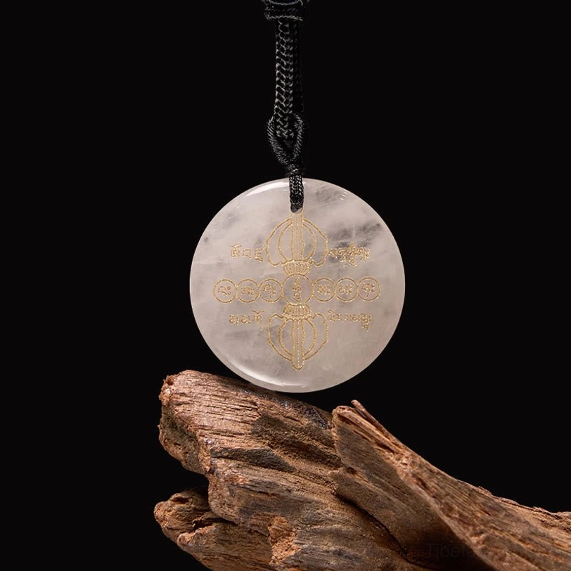 Clear white crystal Vajra Dorje Tibetan necklace pendant with golden Sanskrit patterns, three-quarter view on dark wooden background