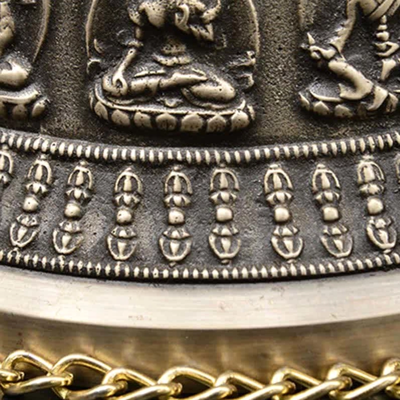 Copper wind chime bell bottom rim close-up revealing embossed ritual amulet protective motifs