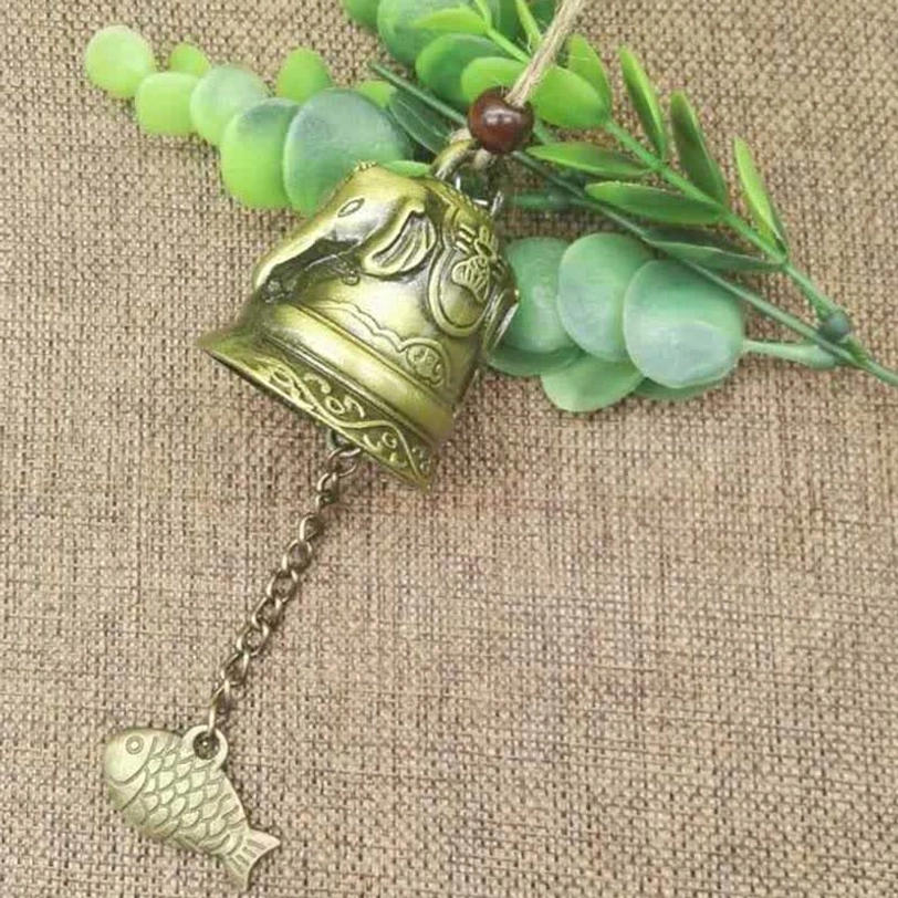 Handcrafted Tibetan feng shui wind chime bell detail showing intricate embossed Buddhist symbols and antique bronze finish