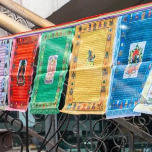 Tibetan windhorse prayer flag banner hanging outdoors on metal railing balcony with five sacred colors and Buddhist scriptures