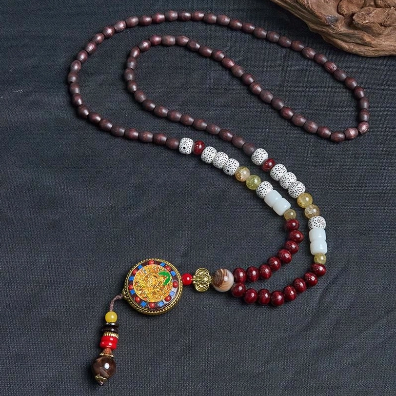 Tibetan prayer bead necklace with mixed spacer beads and tassel pendant on dark background