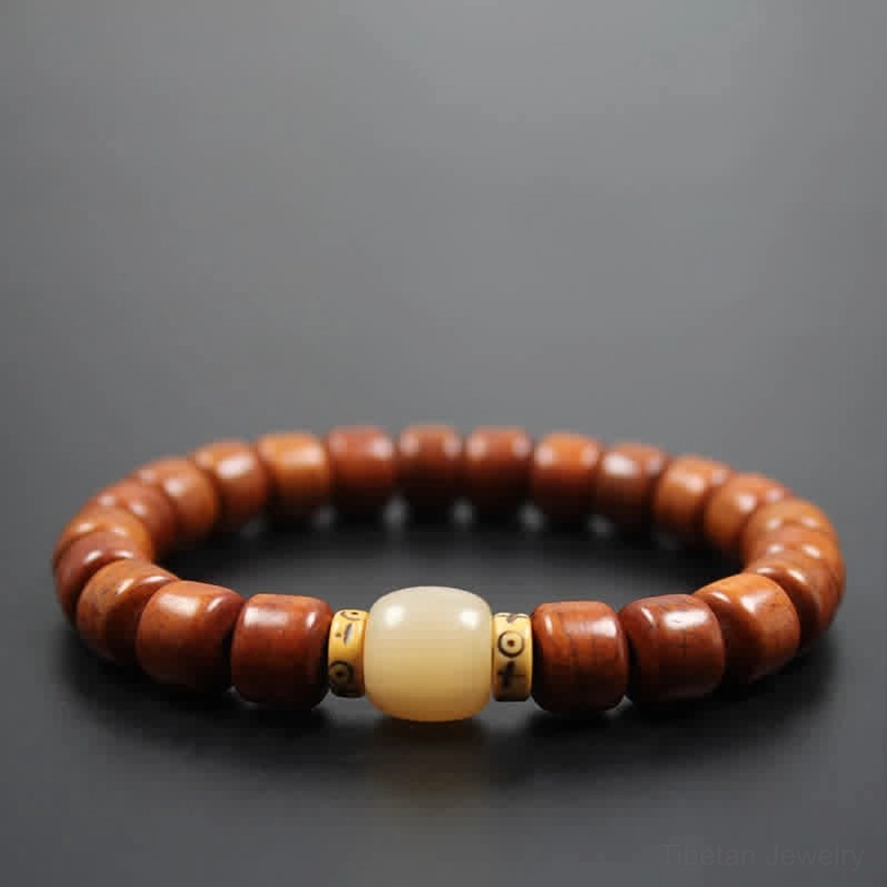 Simple Tibetan wooden bead bracelet with dark brown barrel beads and brass-toned metal spacers on gray background