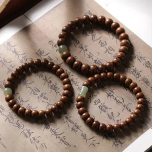 Three handmade Tibetan prayer bracelets with wooden and jade beads arranged on ancient calligraphy paper