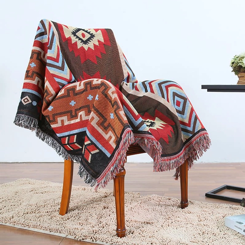 Artisan-crafted Tibetan blanket with full geometric pattern and fringe edges draped over wooden chair