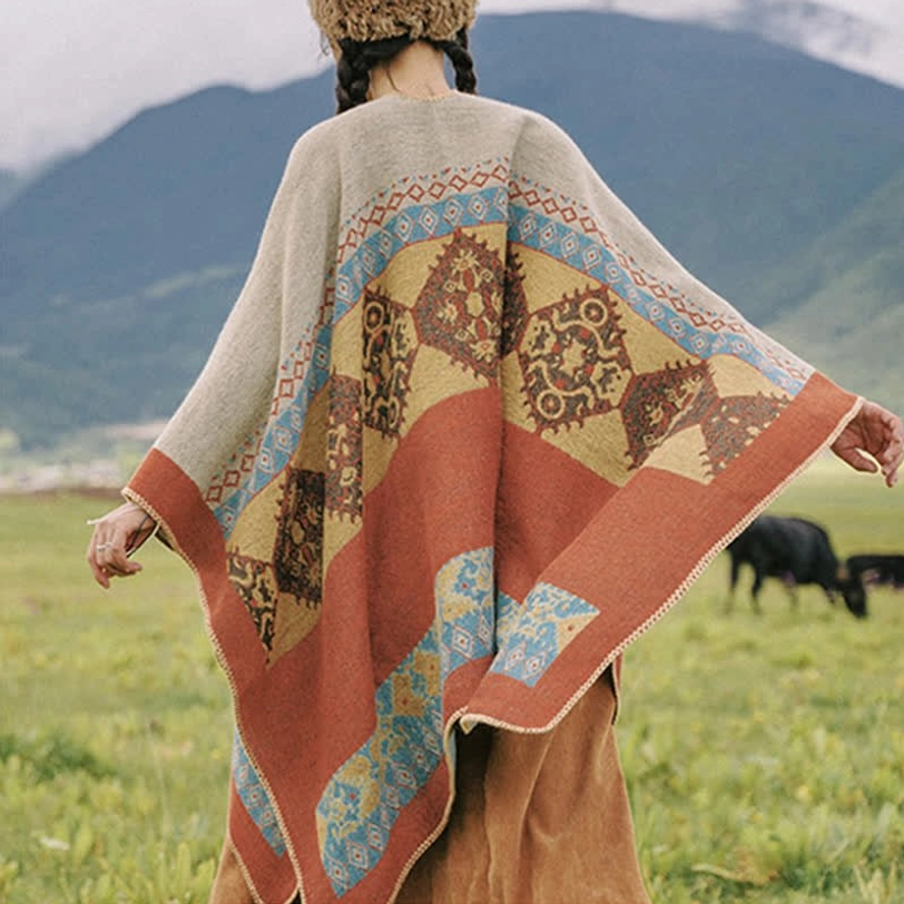 Oversized wrap poncho full back view with complete ethnic pattern coverage and loose fit on mountain grass pasture