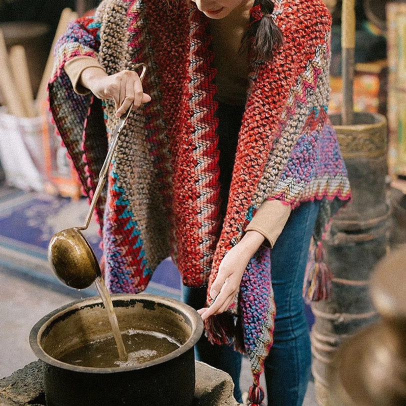 Red and multi-color ethnic Tibetan wrap poncho shawl with tassel pendants and loose wrap fit, low front view in kitchen