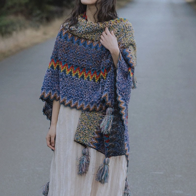 Front three-quarter perspective of foldable Tibetan wrap shawl with multiple tassel pendants and colorful chevron edges