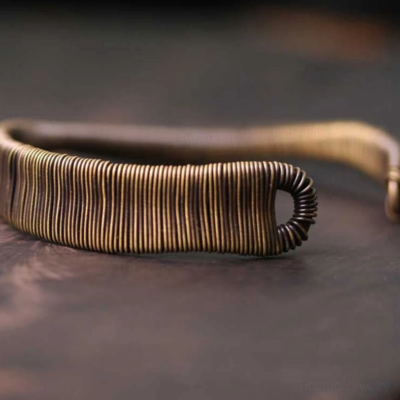 Low close-up side view of open cuff bracelet showing hook-shaped open ends and thick wire-wrapped body