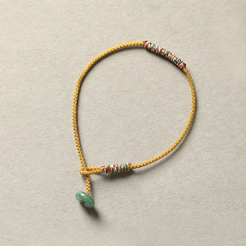Yellow braided Tibetan protection bracelet featuring colorful woven accents and genuine green aventurine bead