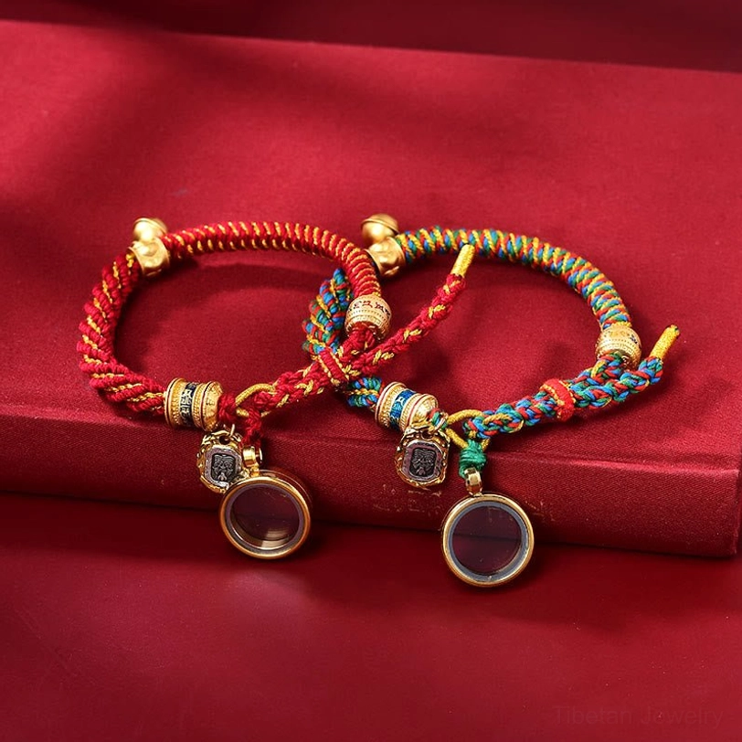 Two Tibetan braided amulet bracelets in red and multicolored styles with round metal locket pendants, scripture charms, and bell accents