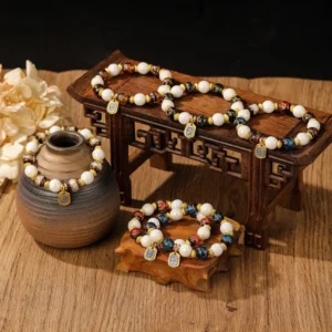 Tibetan charm bracelets with glazed porcelain beads and engraved metal pendants displayed on vintage wooden surface