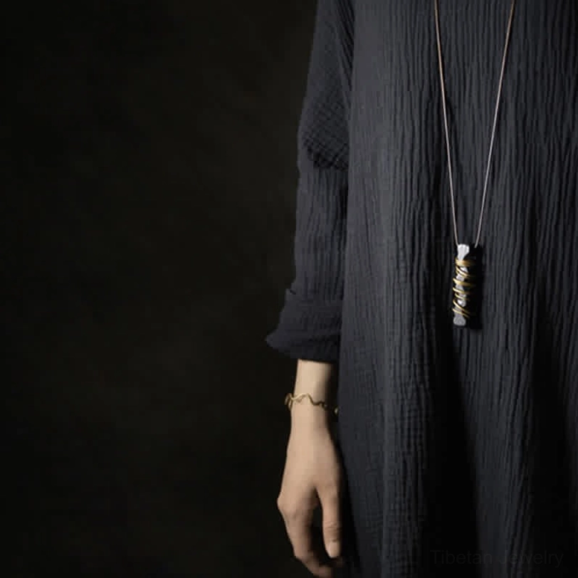 Tibetan spiritual necklace flat lay with ebony wood pendant and brown wax cord on neutral background
