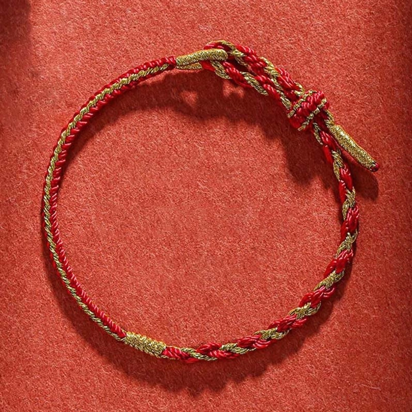 Complete red and gold Tibetan protection bracelet with sacred knot on fabric background
