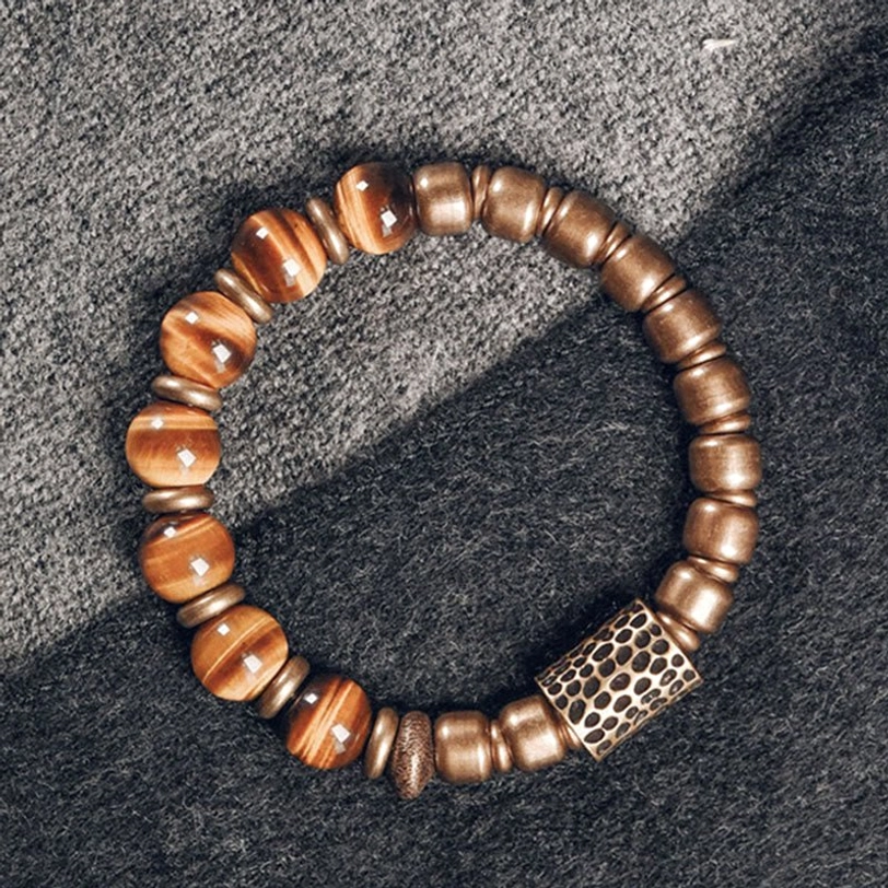 Handmade tiger eye beaded bracelet with hammered rectangular copper accent on gray wool fabric