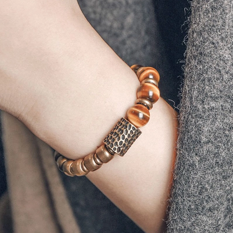 Tiger eye stone protection bracelet worn on wrist with gray sweater, side view showing hammered copper spacer