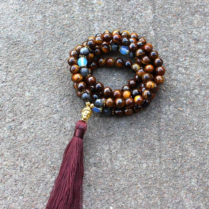 Tiger eye Buddha mala necklace coiled display showing burgundy tassel and gold Buddha spacer