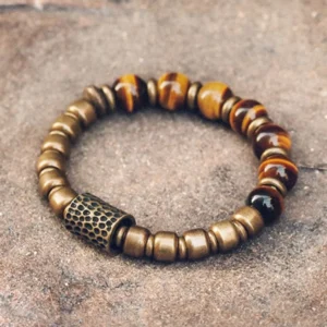 Tiger eye stone copper protection bracelet with hammered metal spacer bead, top-down full view on rustic stone surface