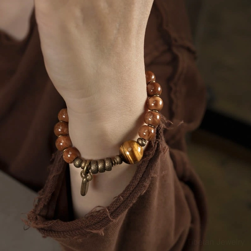 Kuka seed tiger eye bracelet worn on wrist with vintage brown clothing backdrop