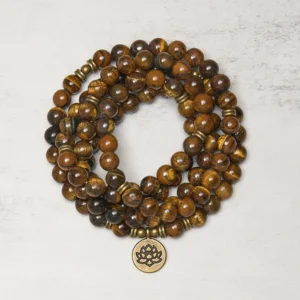 Tiger Eye 108 beads Tibetan mala bracelet with bronze lotus charm, flat lay top view on textured surface