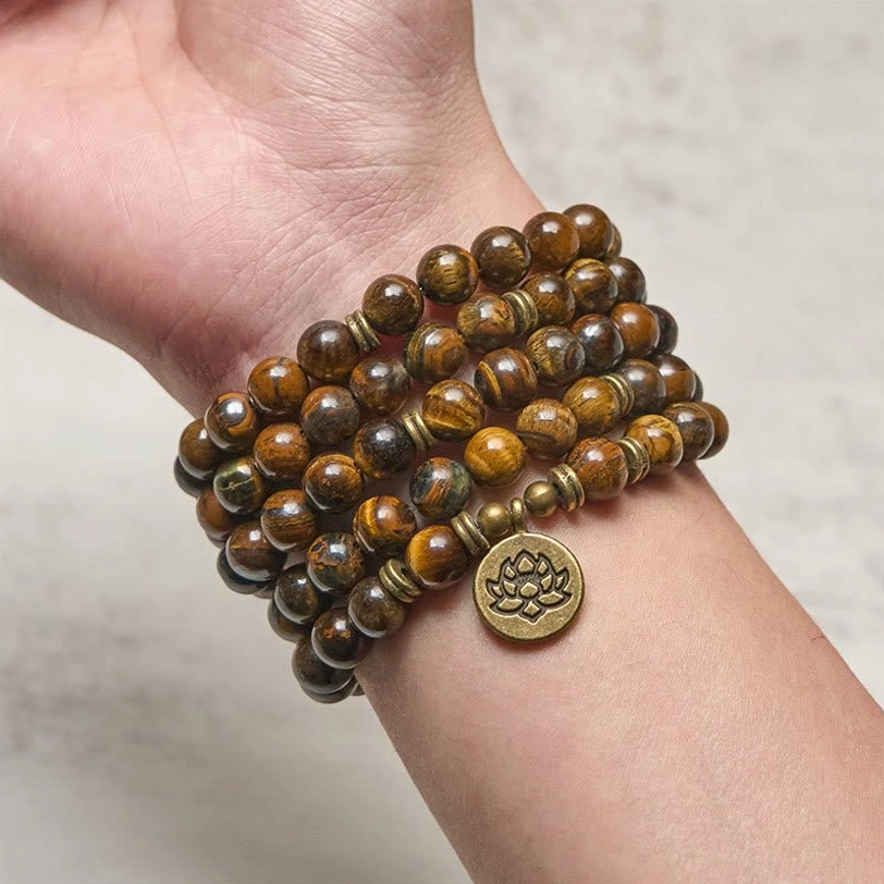 Tiger eye mala bracelet worn on wrist, close-up showing 8mm beads and bronze lotus charm on human arm