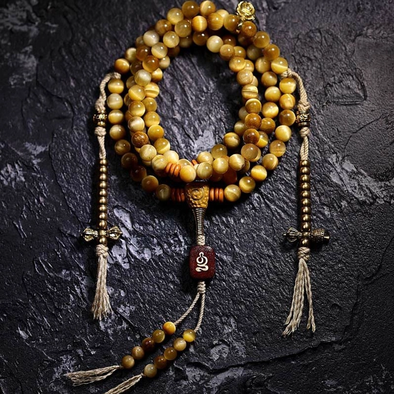 Complete 108-bead Tiger Eye mala set with dual Vajra tassel counters, carved wooden pendant, and protective guru bead flat lay
