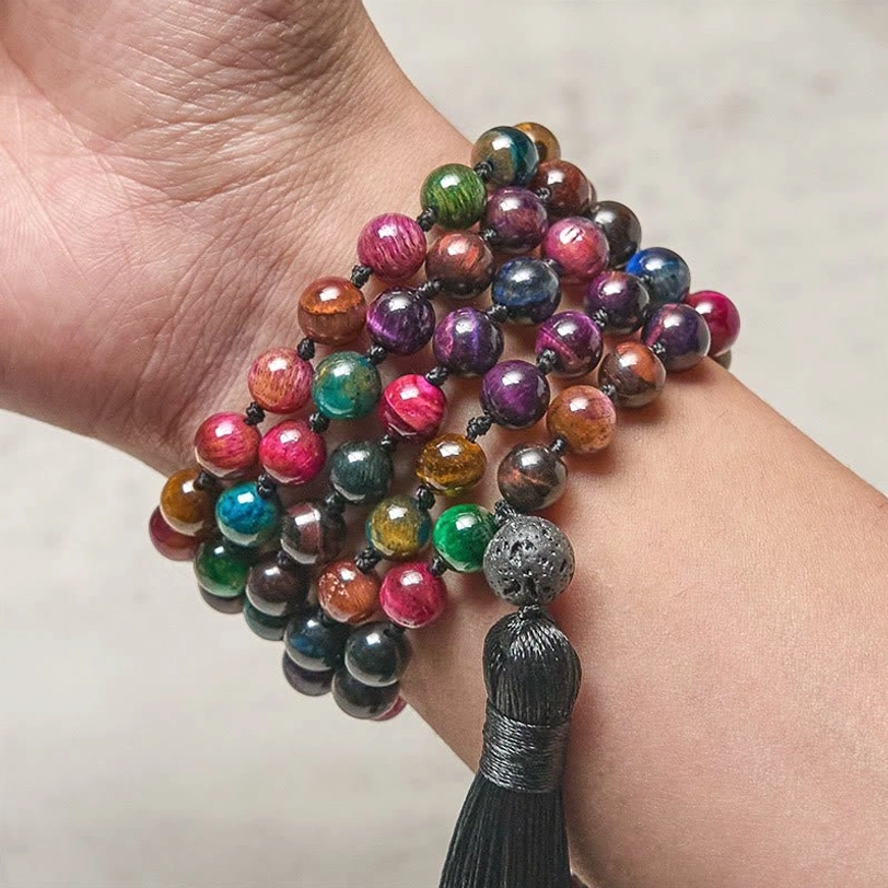 Woman wearing multicolor tiger eye mala necklace on wrist showing colorful beads and tassel worn as meditation bracelet