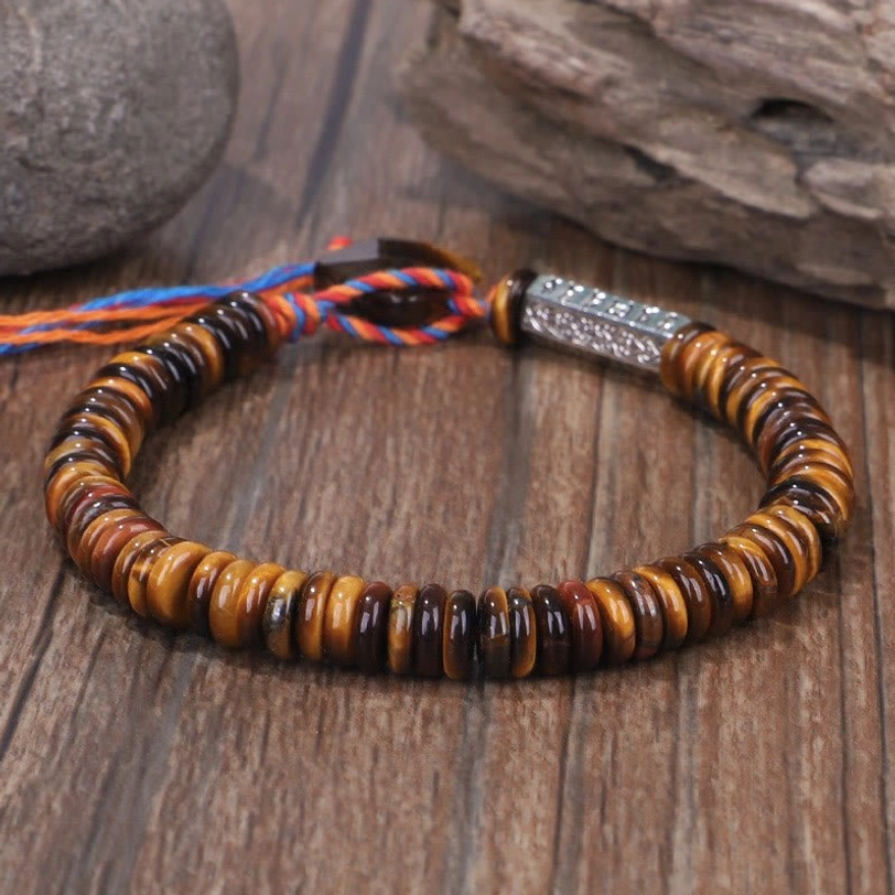 Tiger eye stone beaded bracelet with polished disc beads and silver metal clasp on wooden surface