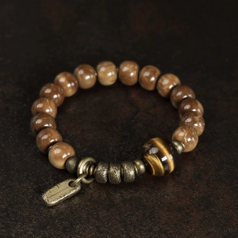 Two-tone brown tiger eye stones with striped central bead and brass hardware on dark background